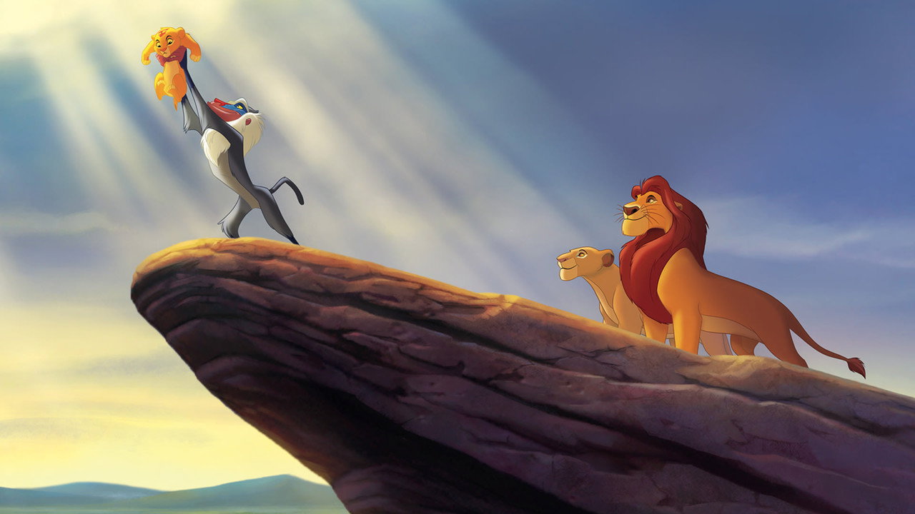 Rafiki holds cub Simba aloft on Pride Rock as Mufasa and Sarabi watch. Light streams down through the clouds.