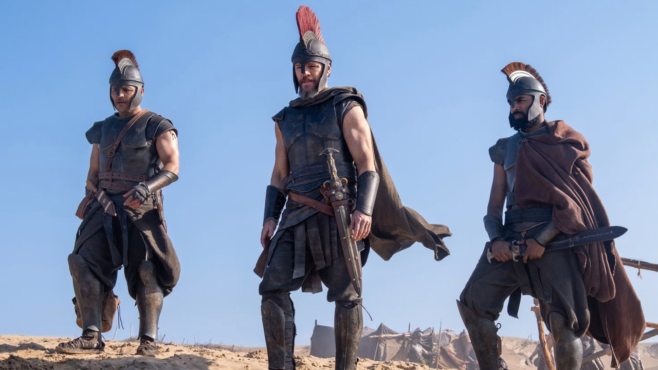 Three warriors cross a dune, Odysseus at the center, from Christopher Nolan's The Odyssey